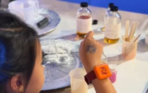 Children smelling natural scent droppers and designing candle jars at a creative workshop in Dubai
