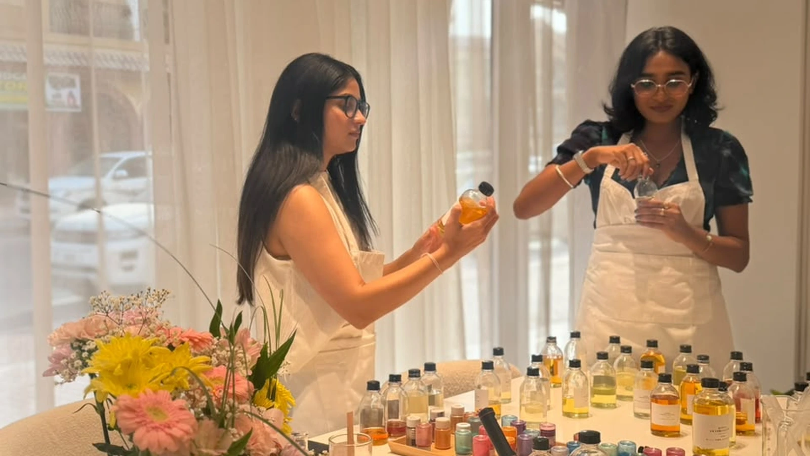 Two best friends laughing and blending custom fragrances at a candle making workshop in Dubai