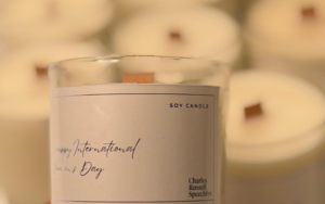 Measuring and centering a braided cotton candle wick in a glass amber jar before pouring wax