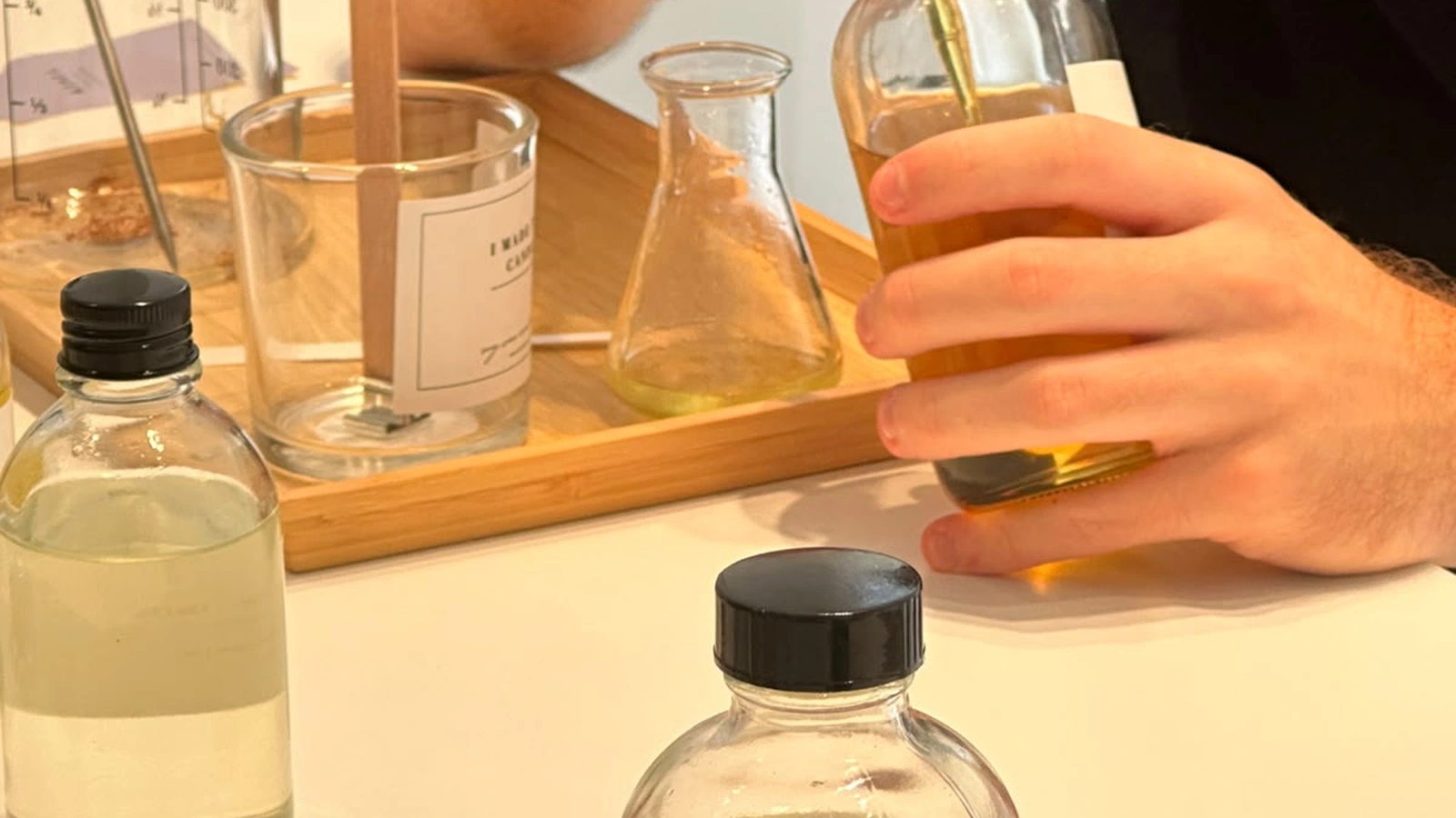 Studio Kinza fragrance blending station featuring scent blotter strips, amber oil droppers, and wax pitchers