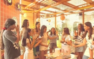 Group of teenage friends laughing and designing custom scented candles at a birthday workshop in Dubai